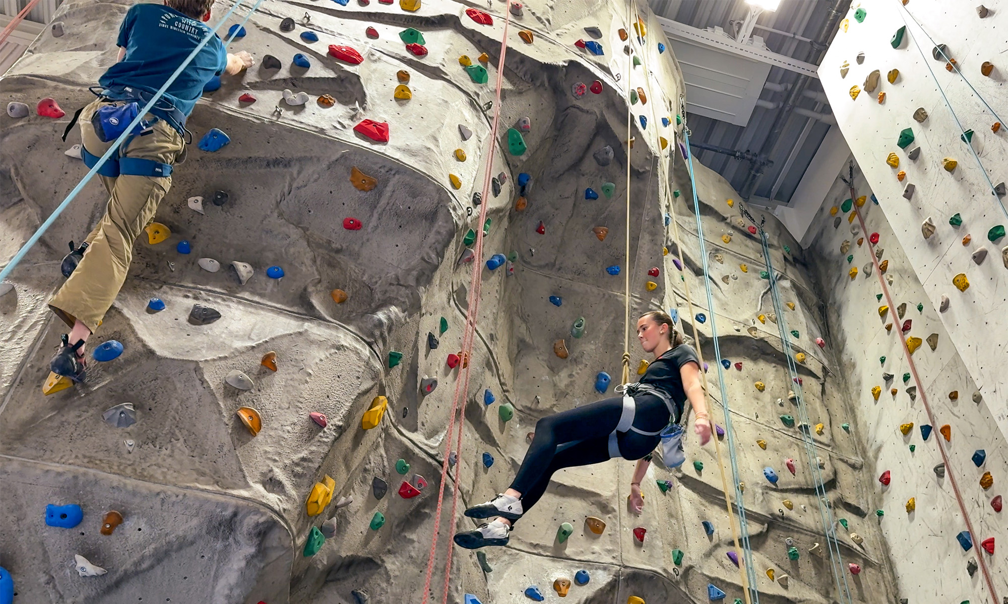 Girl in safety harness is lowered after finished climbing