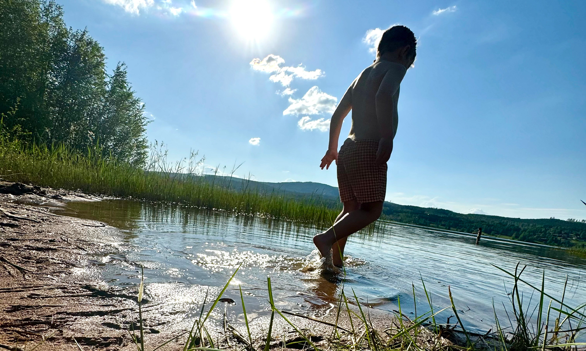 Sommarbild med barn som springer i en sjö